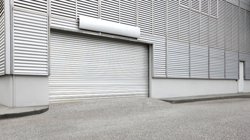 Industrial building with silver corrugated cladding and closed roller shutter door