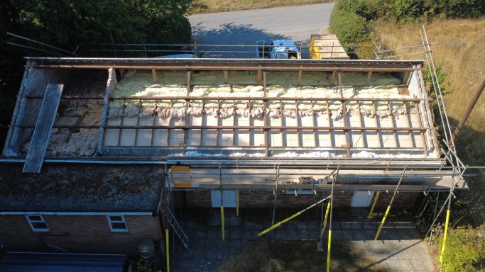 New insulated metal roof installed after asbestos roof removal on village hall